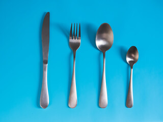 set of tableware. Knife fork spoon made of yellow metal imitating gold on a blue background