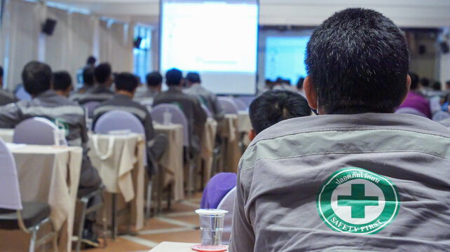 A picture of a workman participating in a knowledge training workshop in a meeting room by staff wearing a robe with Thai letters written as Safety first and copy space.