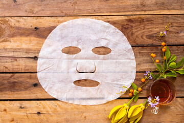 natural aroma sheet mask extract honey herbal vegetation  health care for skin face essence face mask and flower ylang ylang arrangement flat lay style on background wooden