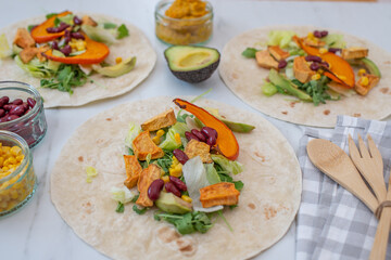 Open vegan tortilla wraps with sweet potato, beans, avocado and pumpkin