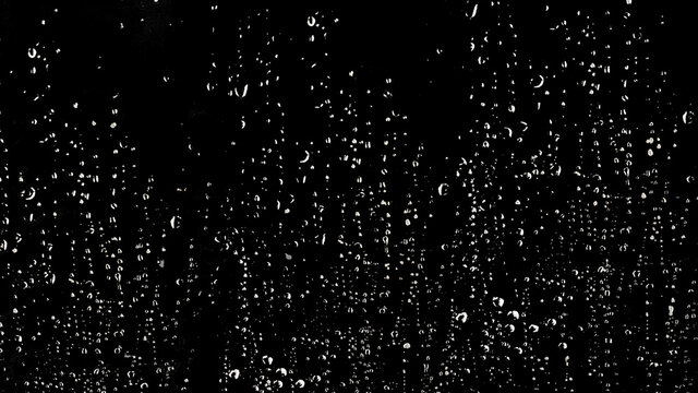 white color of rain drop or water drop on the glass on the black background when rainny season coming.