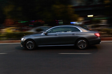 Panning technique of grey car which is going to market at night on the road