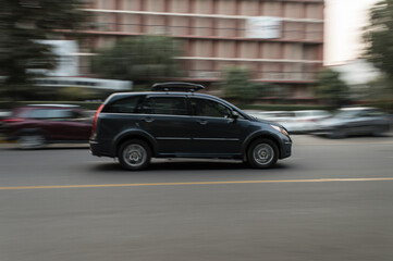 Panning technique of grey car which is going to market at evening on the road