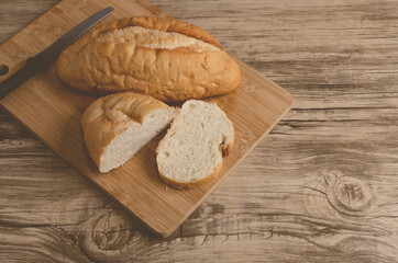 Pan blanco cortado sobre tabla de corte y mesa de madera.