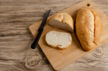 Pan blanco cortado sobre tabla de corte y mesa de madera.