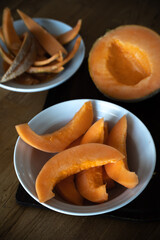 on the plate wood table with melon slices. In the background half a melon and the remains of the skins