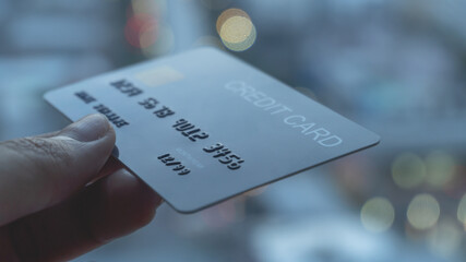 Woman hands holding a blue credit card selective focus on card number and using a smartphone for shopping online or internet banking. Online shopping concept.