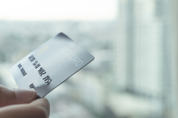 Woman hands holding a blue credit card for shopping online or internet banking with city view background. Online shopping concept.