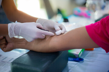 Obraz na płótnie Canvas Close-up of nurse hands introducing the coronavirus vaccine introducing needle into vein of arm.