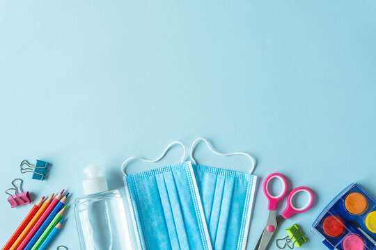 School supplies and coronavirus prevention items on blue background.