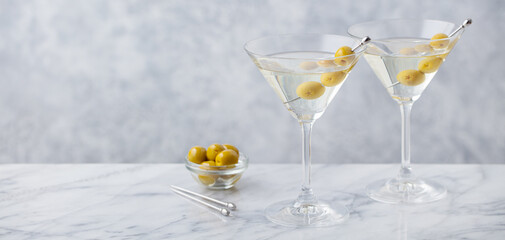 Martini cocktail with green olives on marble table background. Copy space. Close up.