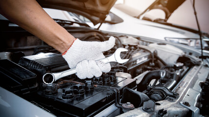 Close-up hands of auto mechanic are using the wrench to repair a car engine. Concepts of car care...