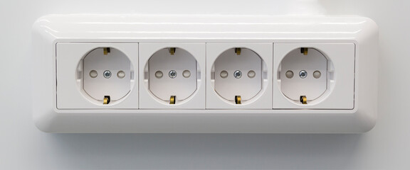 Four electric white outlet socket on gray wall EU standard. Banner format.