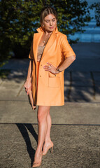 Woman in orange coat at street, woman outfit. Fancy style for ladies, autumn colors and fashion 