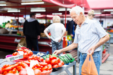 retired european man buying tomatoes in market