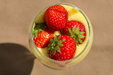 Sweet vanilla dessert with fresh strawberries served in a glass, from above