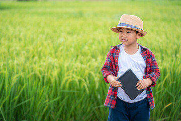 Happy Asian Little boy with a tablet interested in learning the surroundings in the green fields, education concept outside the classroom Educational freedom  In the age of technology