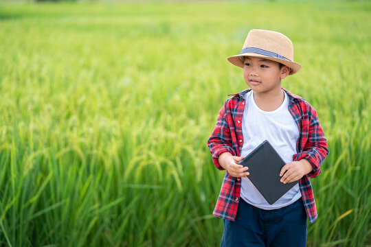Happy Asian Little boy with a tablet interested in learning the surroundings in the green fields, education concept outside the classroom Educational freedom  In the age of technology