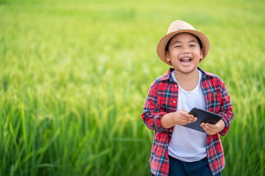 Happy Asian Little boy with a tablet interested in learning the surroundings in the green fields, education concept outside the classroom Educational freedom