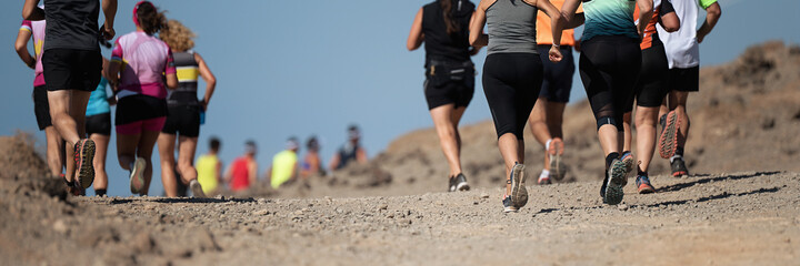 Runners running shoes on trail run. Ultra running athletes legs close up on running in rock path trail	