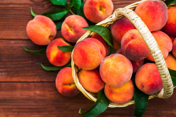 Freshly picked peaches in basket on a brown wooden background. Ripe peaches in basket on wooden...