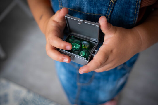 Ni&ntilde;a sosteniendo una caja llena de canicas verdes