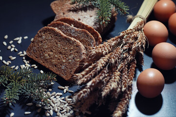 Fresh loaves of bread with wheat and gluten on a black table. Bakery and grocery concept. Fresh, healthy sorts of rye and white loaves food closeup. Fresh homemade bread with cereals.