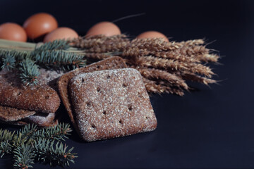 Fresh loaves of bread with wheat and gluten on a black table. Bakery and grocery concept. Fresh, healthy sorts of rye and white loaves food closeup. Fresh homemade bread with cereals.