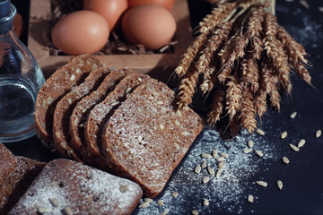 Fresh loaves of bread with wheat and gluten on a black table. Bakery and grocery concept. Fresh,...