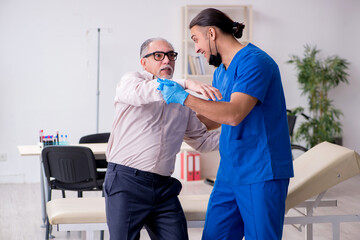 Old patient visiting young male doctor in blood sampling concept