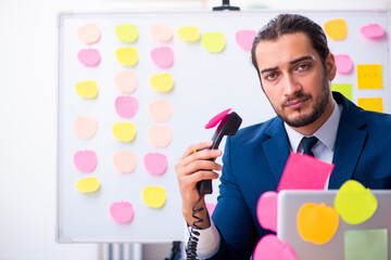Young male employee in conflicting priorities concept