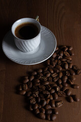 A cup of boiled coffee, coffee beans are next to it.
