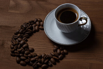 A cup of boiled coffee, coffee beans are next to it.