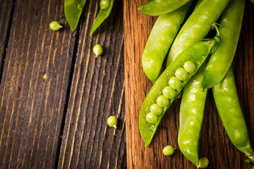 Pods of green peas on a old wooden background close up, soft focus