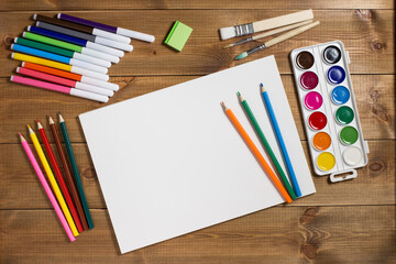 Assortment of stationery for drawing on wood background. Colored pencils, paints, felt tips, brushes for children's creativity. Copy space. Top view. Flat lay