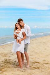 Young family with a toddler relax on the sea coast