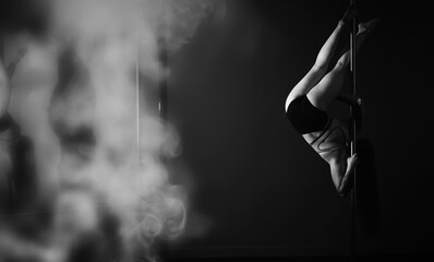 The dancer on the pylon in the studio. Girl doing exercises on a sports equipment.