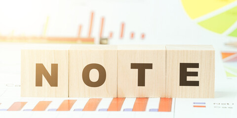 word note with letters on wooden cubes on table with graphs