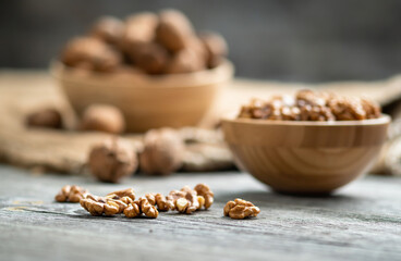 Fresh walnut kernels and whole walnuts in a bowl on rustic old wooden table. Healthy organic food, BIO viands, natural background. Copy space for your advertising text message