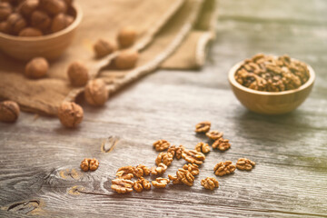 Fresh walnut kernels and whole walnuts in a bowl on rustic old wooden table. Healthy organic food, BIO viands, natural background. Copy space for your advertising text message