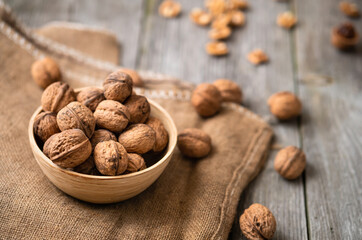 Whole walnuts in a bowl and jute bag on rustic old wooden table. Healthy organic food, BIO viands, natural background. Copy space for your advertising text message