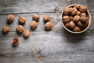 Whole walnuts in a bowl and on rustic old wooden table. Healthy organic food, BIO viands, natural background. Copy space for your advertising text message
