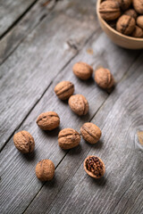 Whole walnuts in a bowl and on rustic old wooden table. Healthy organic food, BIO viands, natural background. Copy space for your advertising text message