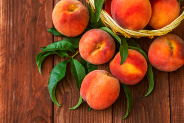 Freshly picked peaches in basket on a brown wooden background. Ripe peaches in basket on wooden table