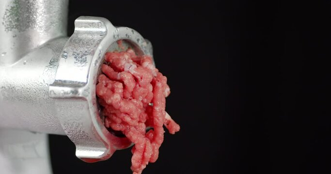 Raw minced meat falls from the meat grinder. 