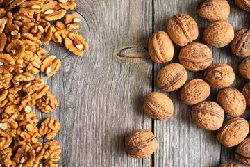 Heap of fresh walnut kernels and whole walnuts on wooden table - natural pattern background detail. Close up of brown surface texture. Healthy organic food, BIO viands, back to nature concept