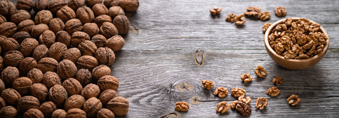 Fresh walnut kernels and whole walnuts in a bowl on rustic old wooden table. Healthy organic food, BIO viands, natural background. Copy space for your advertising text message