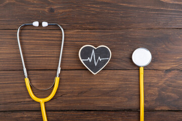 Workplace of a doctor. Stethoscope and little heart on wooden desk background