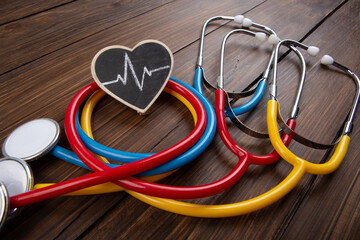 Workplace of a doctor. Colorful Stethoscopes and little heart on wooden desk background -...
