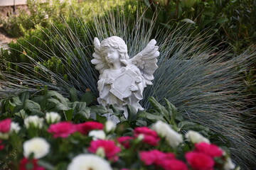 Engel mit Harfe zwischen Blumen auf einem Grab